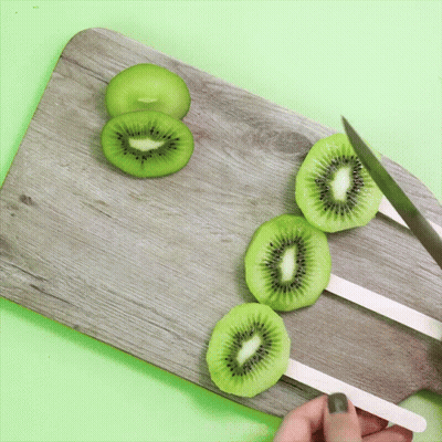 Person Cutting Kiwi Slices GIF