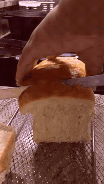 Person Cutting Loaf Of Bread On Wire Rack GIF