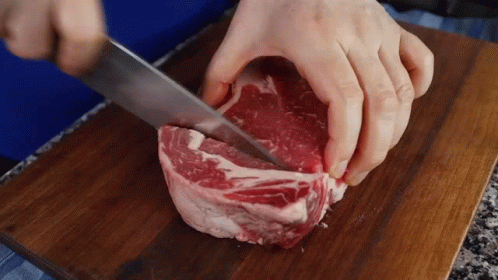 Person Cutting Meat With Knife On Wooden Cutting Board GIF
