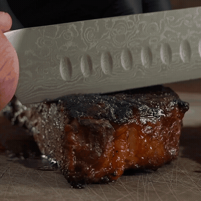 Person Cutting Meat With Patterned Knife GIF