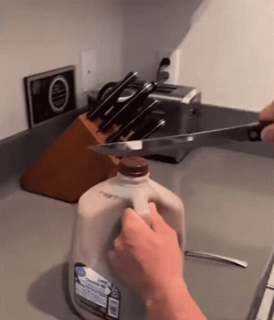 Person Cutting Milk Gallon With Knife GIF