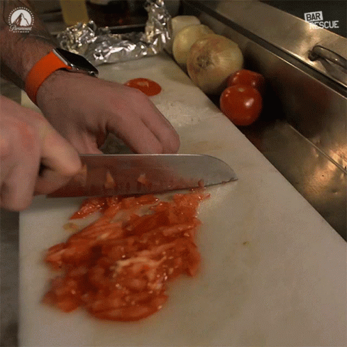 Person Cutting Tomatoes On Cutting Board With Paramount Logo GIF