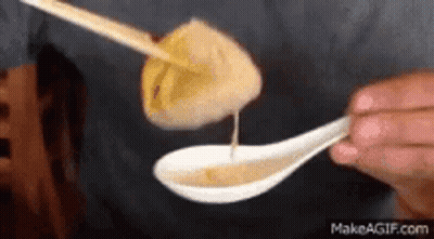 Person Dipping Dumpling Into Spoon Of Sauce GIF