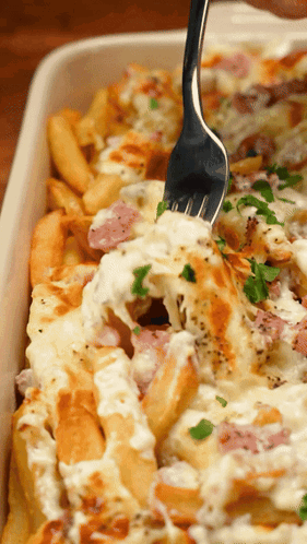 Person Dipping Fork Into Casserole Dish With Fries And Cheese GIF
