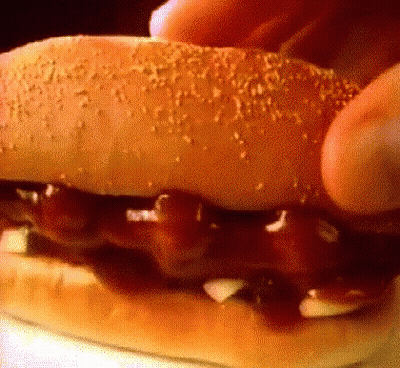 Person Eating Hamburger With Ketchup And Onions GIF