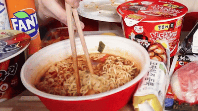 Person Eating Noodles With Chopsticks In Red Bowl Next To Fanta GIF