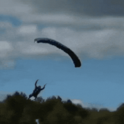 Person Flying Parachute Over Field GIF