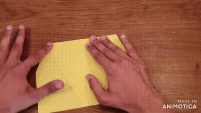 Person Folding Yellow Paper On Wooden Table GIF