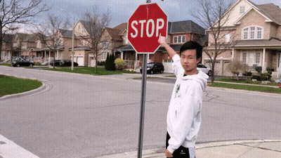 Person Hanging Upside Down Next To Red Stop Sign GIF
