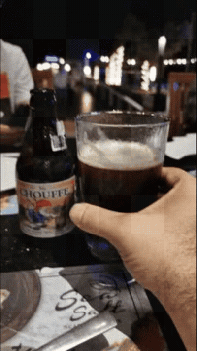 Person Holding Beer Beside Chouffe Bottle GIF