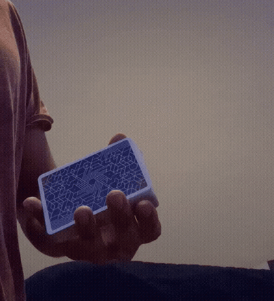 Person Holding Blue Playing Card With Geometric Pattern GIF