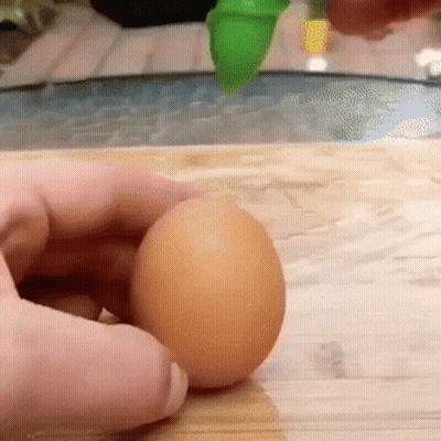 Person Holding Brown Egg On Wooden Cutting Board GIF