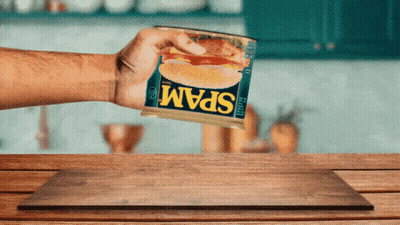 Person Holding Can Of Spam On Wooden Table GIF