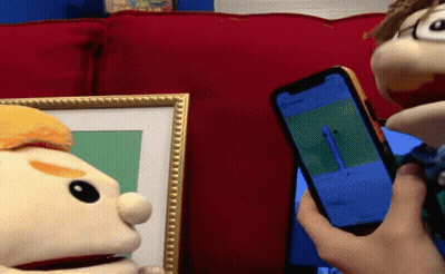 Person Holding Cell Phone Before Two Puppets GIF