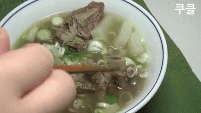 Person Holding Chopsticks Over Bowl Of Soup With Meat And Onions GIF