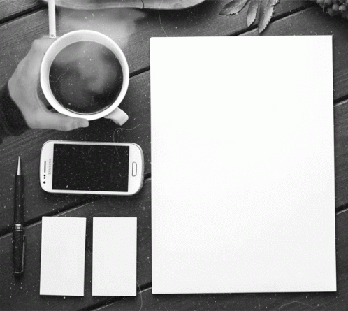 Person Holding Coffee Next To Phone And Paper GIF