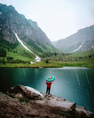 Person Holding Colorful Umbrella In Rain Near Lake GIF