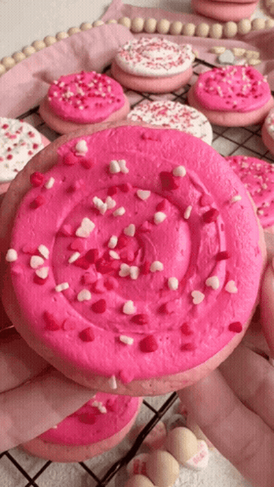 Person Holding Cookie With Pink Frosting And Sprinkles GIF