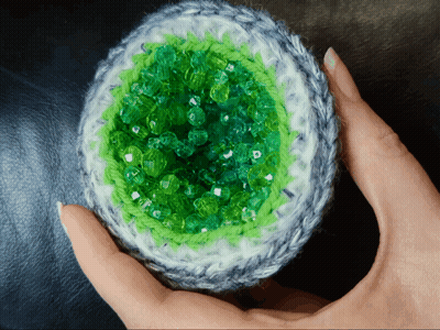 Person Holding Crocheted Object With Green Beads GIF