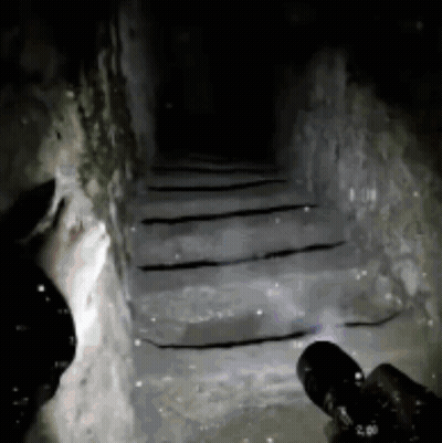 Person Holding Flashlight in Dark Tunnel