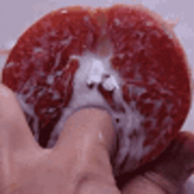 Person Holding Grapefruit Slice With Juice GIF