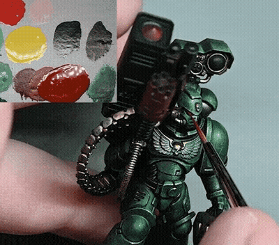 Person Holding Green Robot And Brush Next To Paint Palette GIF