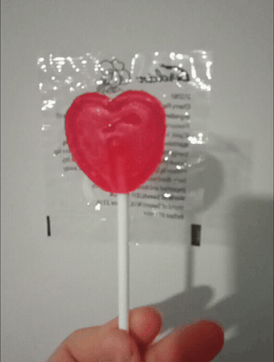 Person Holding Heart Lollipop In Front Of Candy Bag GIF