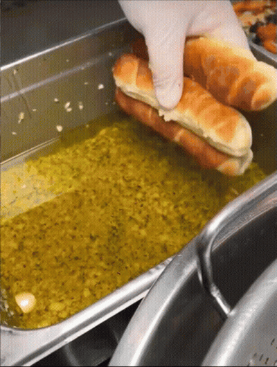 Person Holding Hot Dog Over Oil GIF