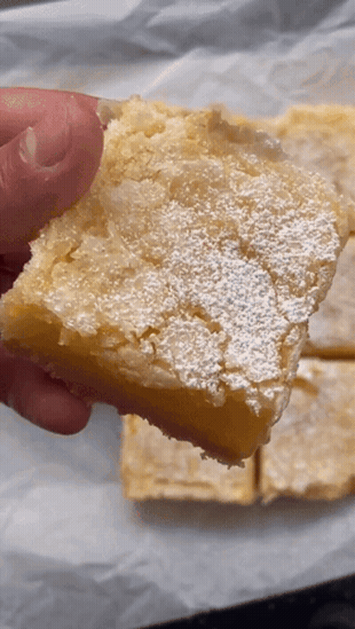 Person Holding Lemon Bar With Powdered Sugar GIF