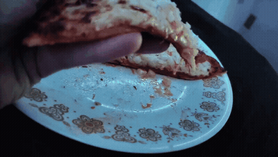 Person Holding Pizza Slice Over Plate With Flowers GIF