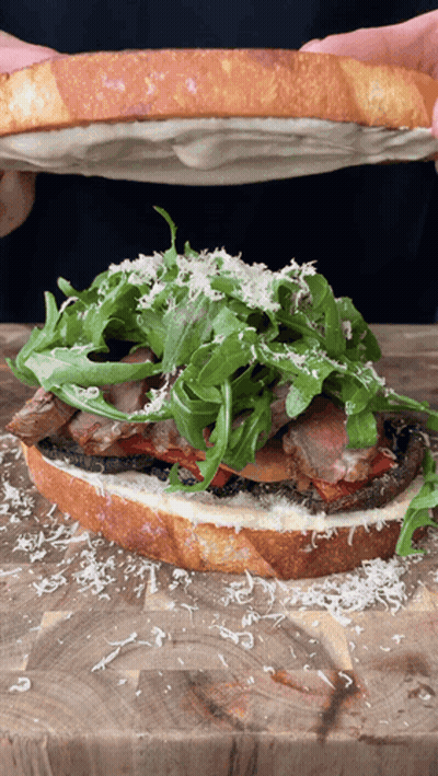 Person Holding Sandwich With Meat And Lettuce GIF