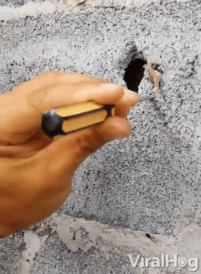 Person Holding Screwdriver At Hole In Concrete Wall GIF