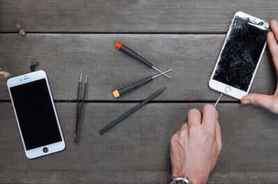 Person Holding Screwdriver Beside Phone With Broken Screen GIF