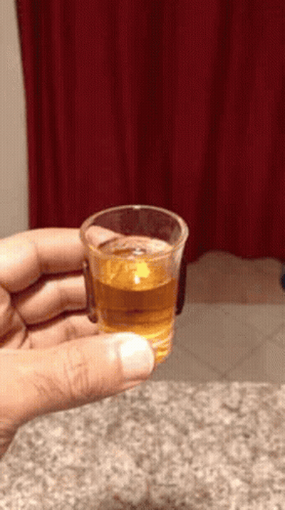 Person Holding Shot Glass With Red Curtain Background GIF