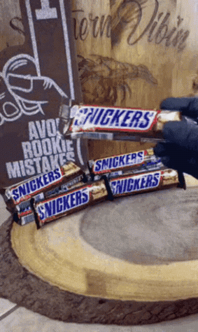 Person Holding Snickers Stack, Avoid Rookie Mistakes Sign GIF