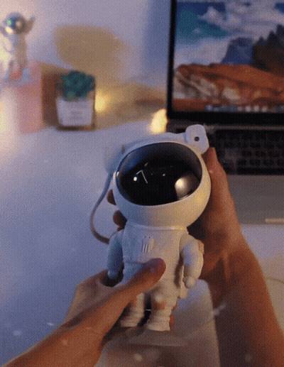 Person Holding Toy Astronaut In Front Of Laptop GIF