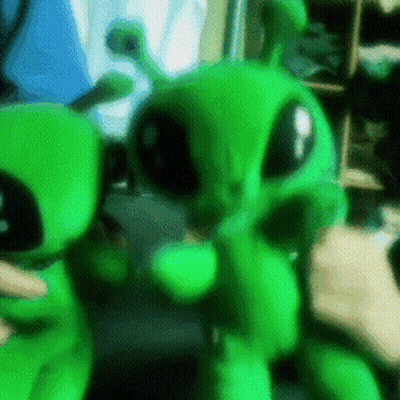 Person Holding Two Green Stuffed Aliens GIF