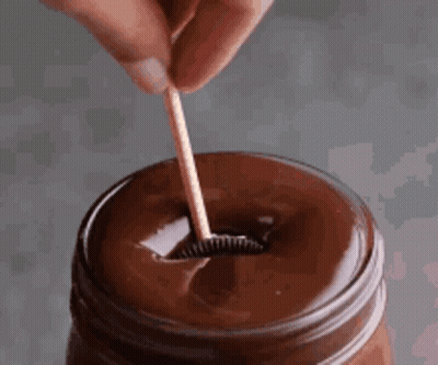 Person Holding Wooden Toothpick In Chocolate Sauce GIF