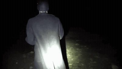 Person In Black Coat Standing In Dark GIF