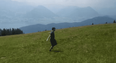 Person In Black Dress Walking In Grassy Field GIF