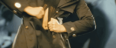 Person In Black Trench Coat Holding Purse GIF