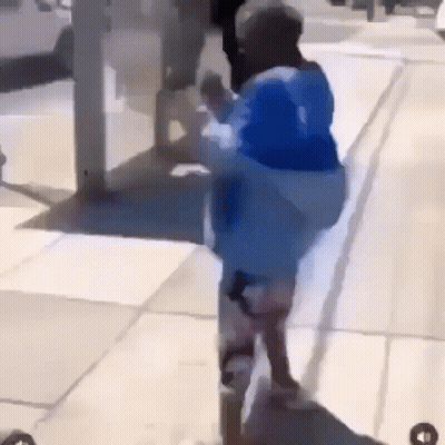 Person In Blue Jacket Walking Down Sidewalk GIF
