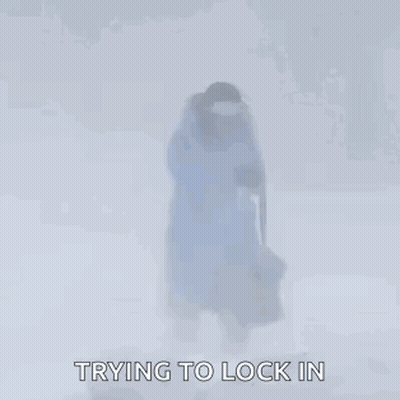 Person In Blue Jacket Walking Through Snow With Bag GIF