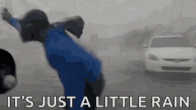 Person In Blue Shirt Dancing In Rain GIF