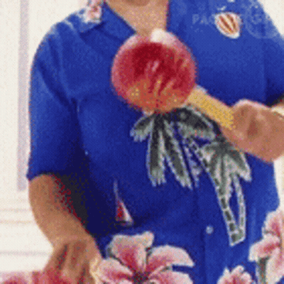 Person in Blue Shirt With Palm Trees Holding Apple