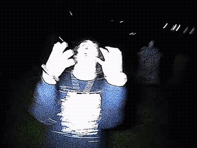 Person In Blue Sweater Covering Face In Dark GIF