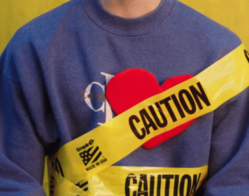 Person In Blue Sweater With Yellow Caution Tape Around Chest GIF