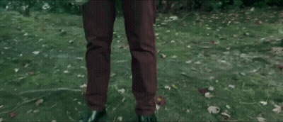 Person In Brown Pants Holding Balloon In Grass GIF