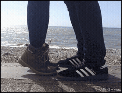 Person In Caterpillar Boots Next To Adidas Shoes GIF