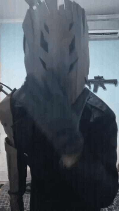 Person In Costume With Gun In Background GIF
